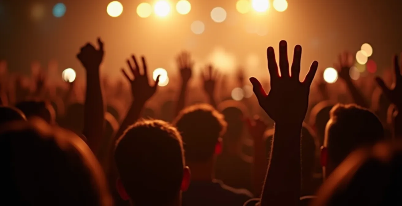 Gros plan sur les mains du public levées doucement pendant une ballade, éclairage tamisé